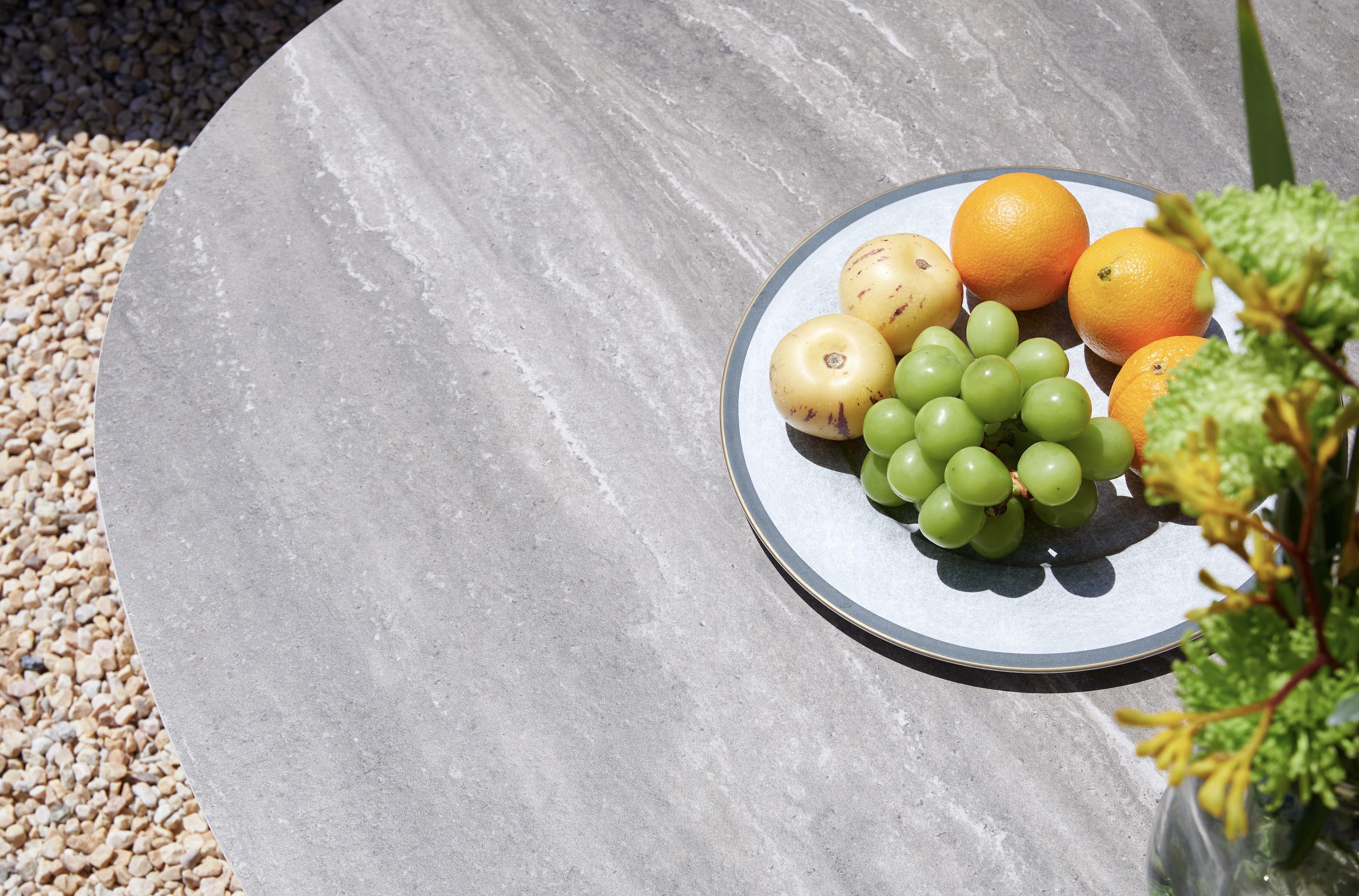 Plateau céramique gris texturé sur table d'extérieur en aluminium design, élégance méditerranéenne, fruits colorés posés.