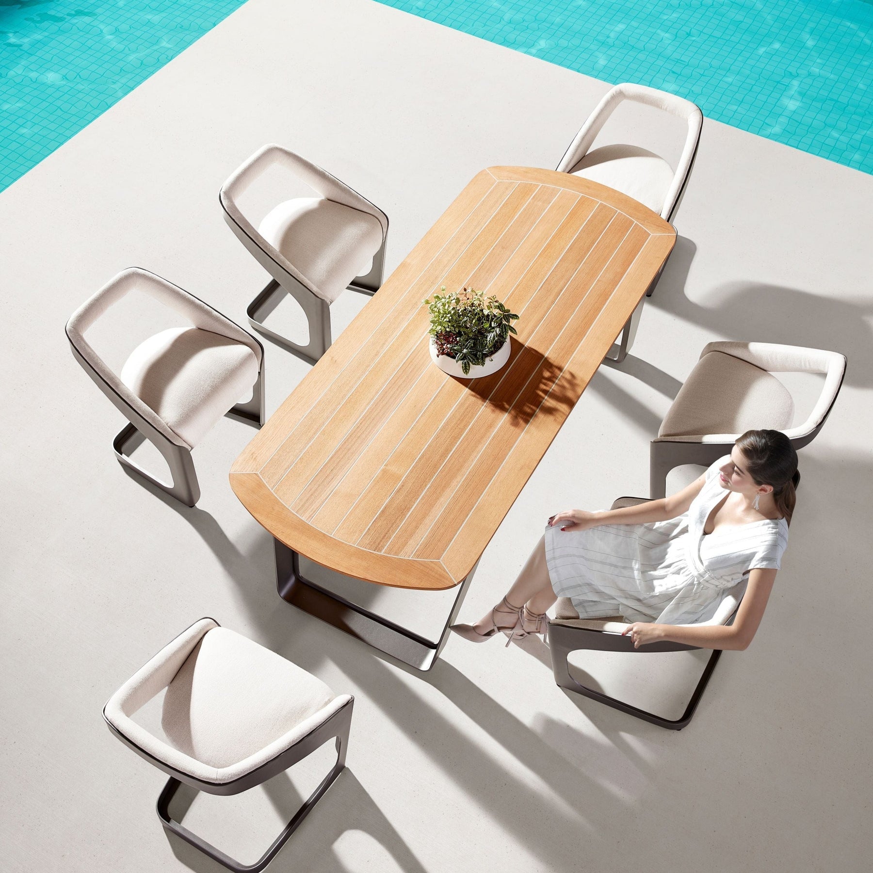 Ensemble repas luxe ONDA en aluminium et teck FSC, table ovale aux lignes courbées, six fauteuils en tissu Sunbrella beige.
