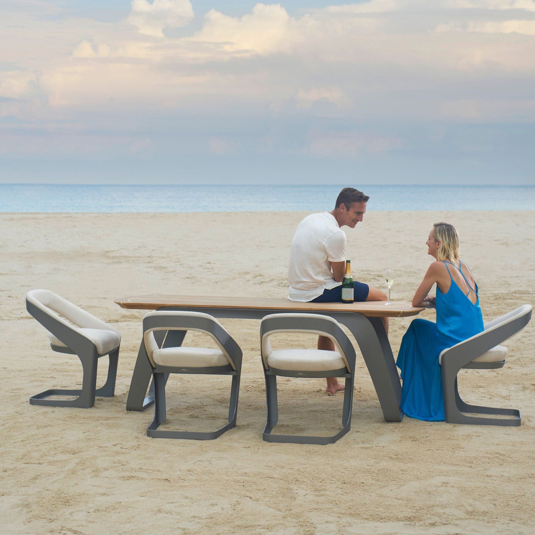 Ensemble repas luxe ONDA en teck FSC et aluminium, chaises courbées avec tissu Sunbrella et quick dry foam, design élégant.