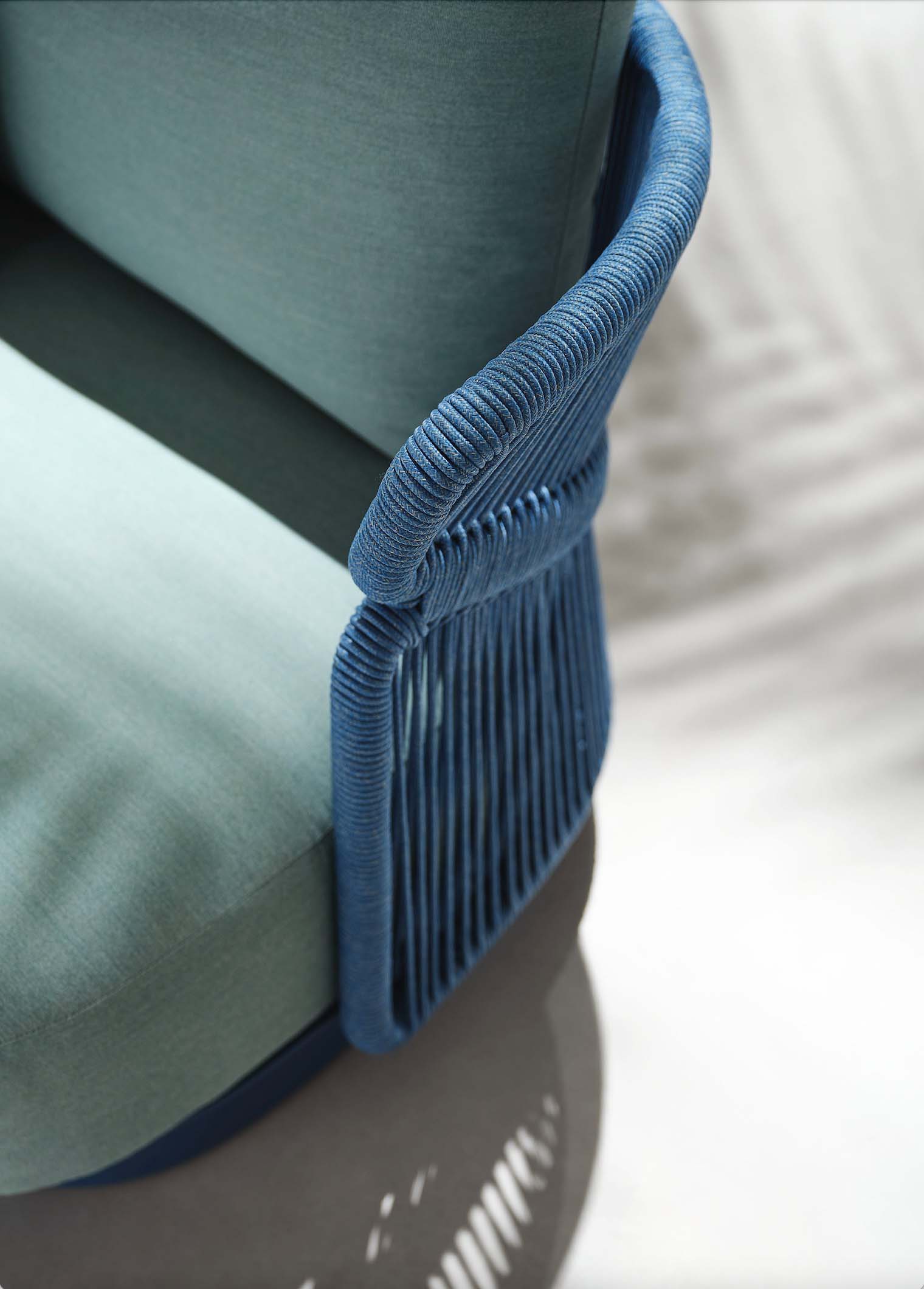 Détail d’accoudoir en corde tressée bleue, design italien luxueux, structure aluminium haut de gamme, coussin bleu profond.