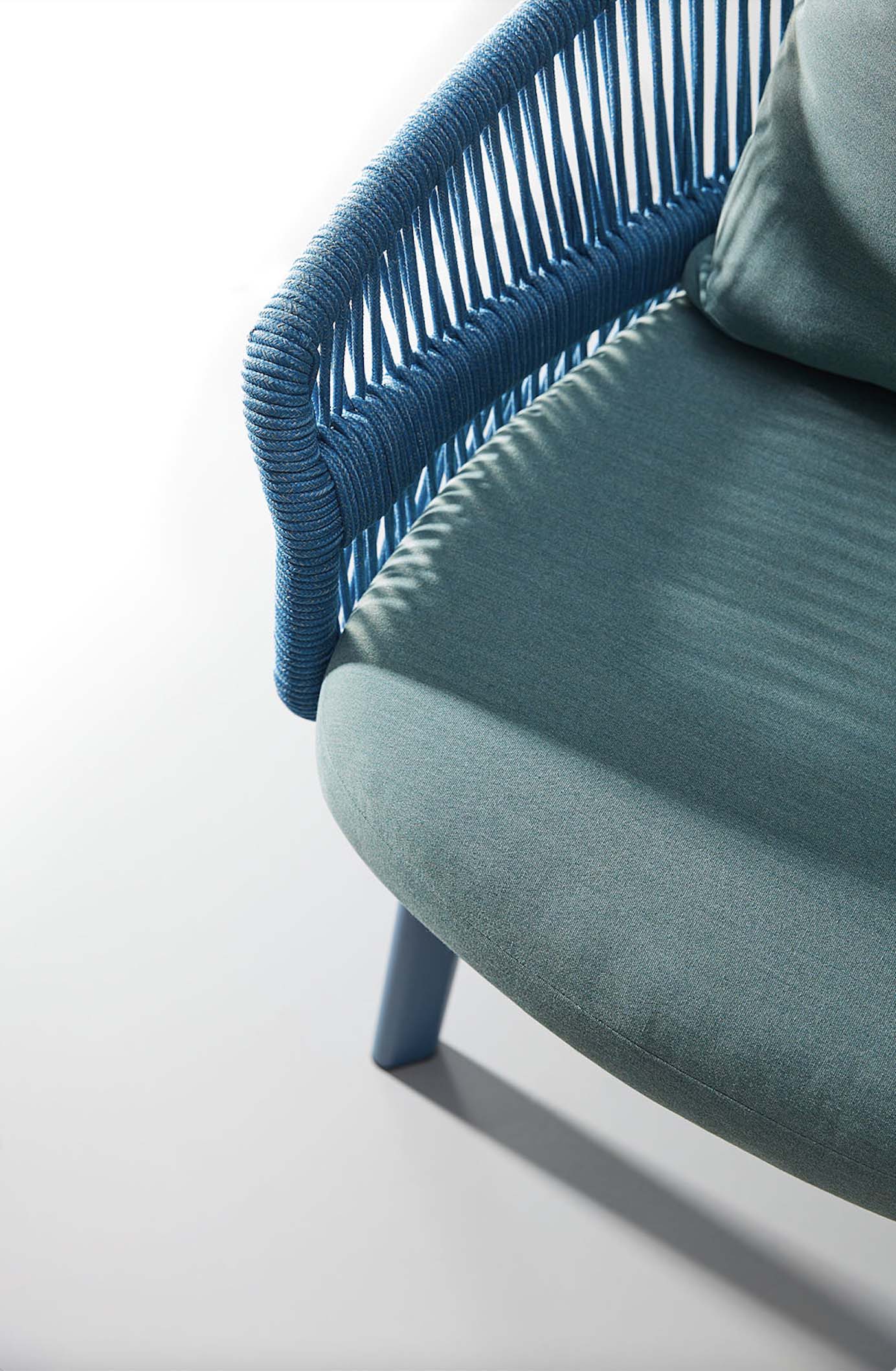 Détail fauteuil luxueux en aluminium bleu avec accoudoir en corde tressée, coussin bleu foncé, design italien haut de gamme.