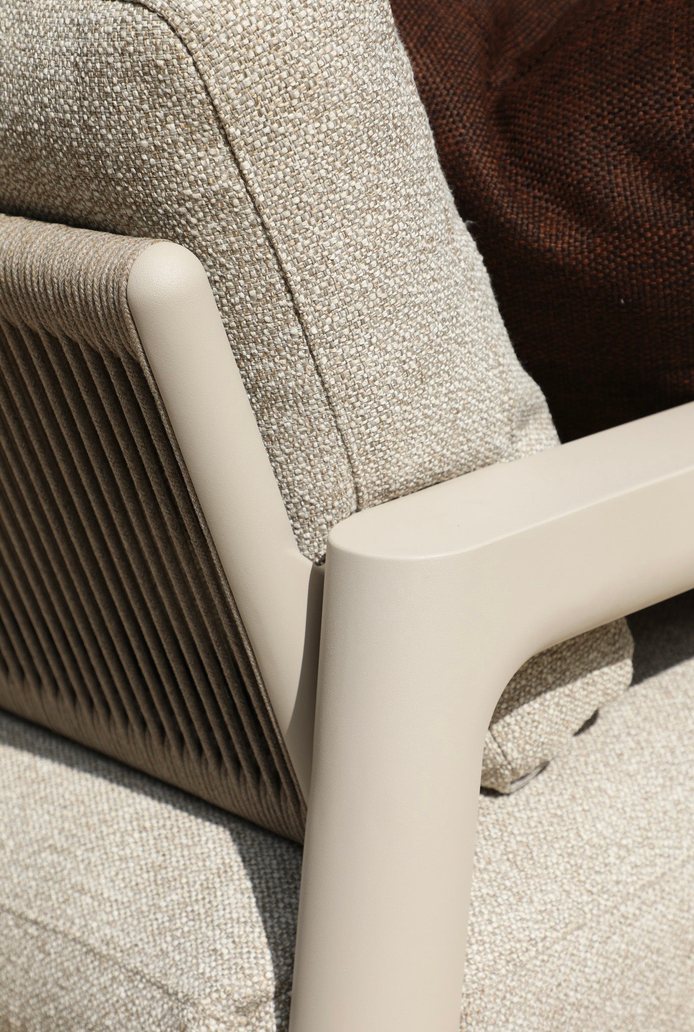 Détail d'accoudoir en aluminium inoxydable beige mat avec corde noire tressée, coussin déhoussable beige clair, design.