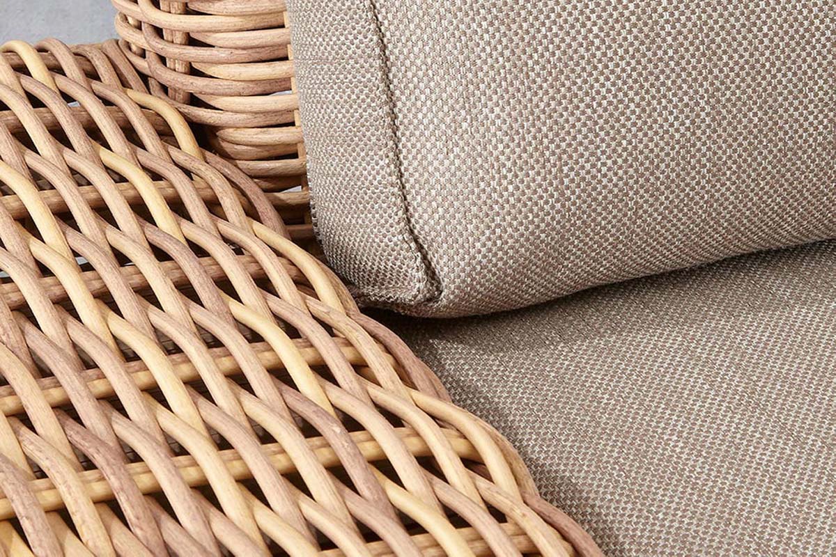 Détail de salon de jardin en résine tressée ronde coloris naturel, coussin beige en tissu 100% oléfine, style cosy rustique.