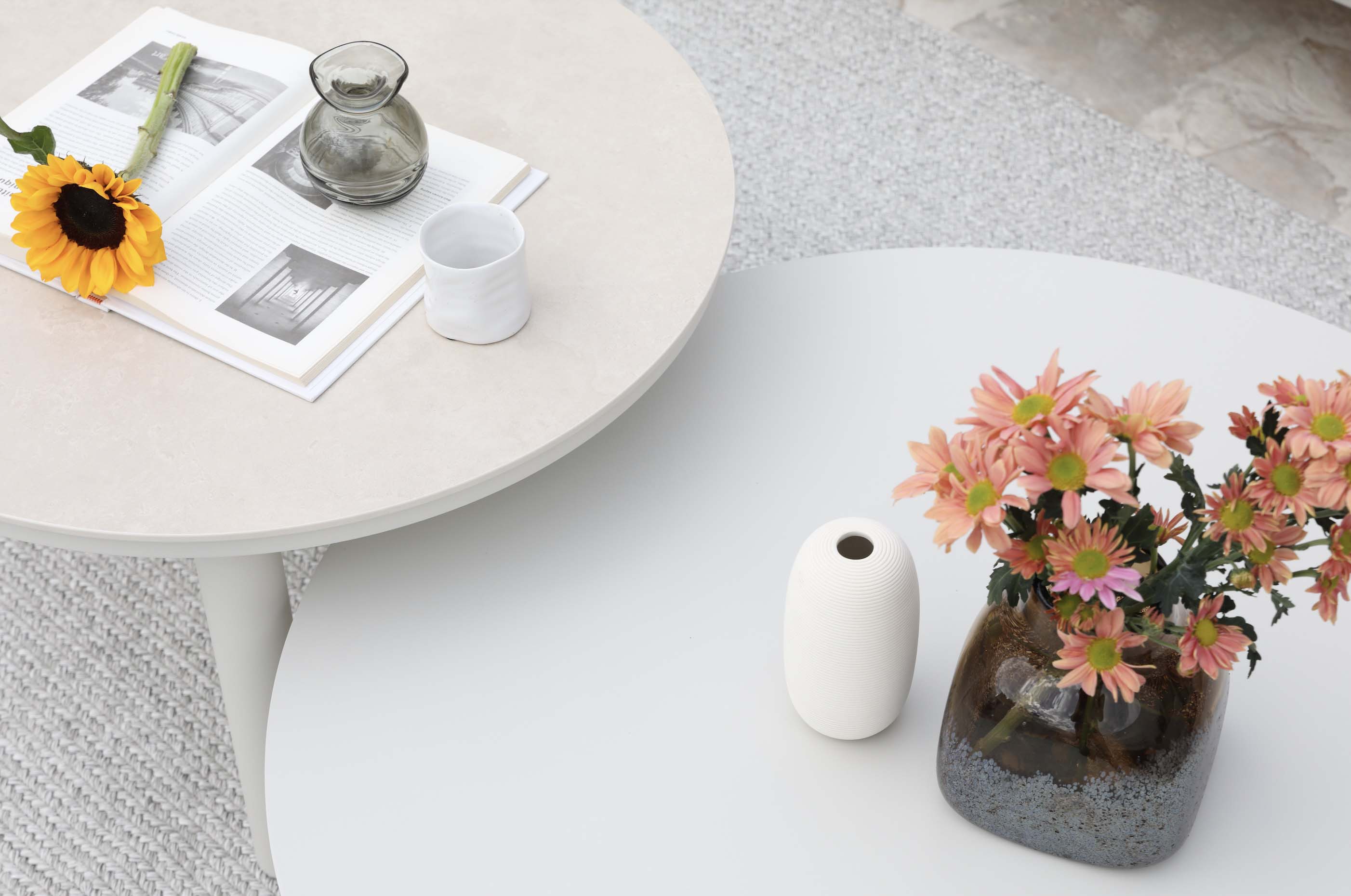 Table basse ronde en céramique blanche avec pieds en aluminium haut de gamme, décorée avec vase noir mat, bouquet de fleurs.