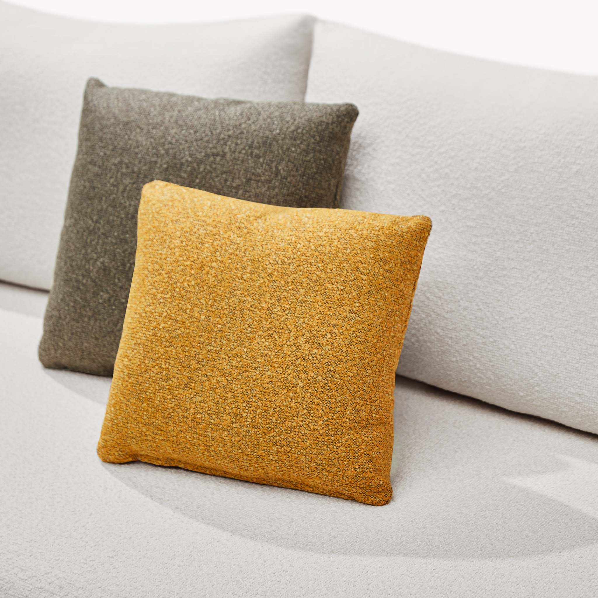 Coussins oléfine luxueux jaune moutarde et taupe sur canapé beige design italien en corde tressée haut de gamme.