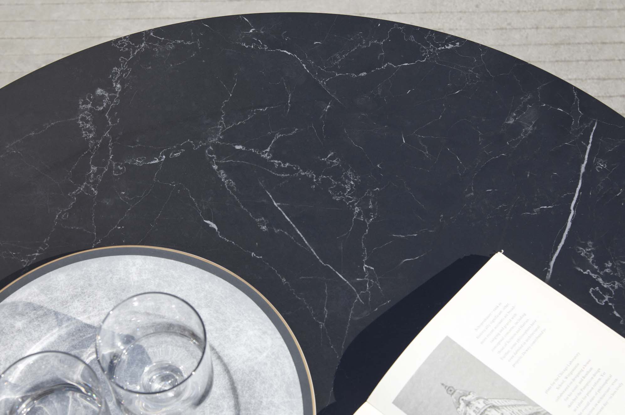 Plateau de table rond noir en marbre effet veiné, design luxe avec finition aluminium haut de gamme, aspect élégant.