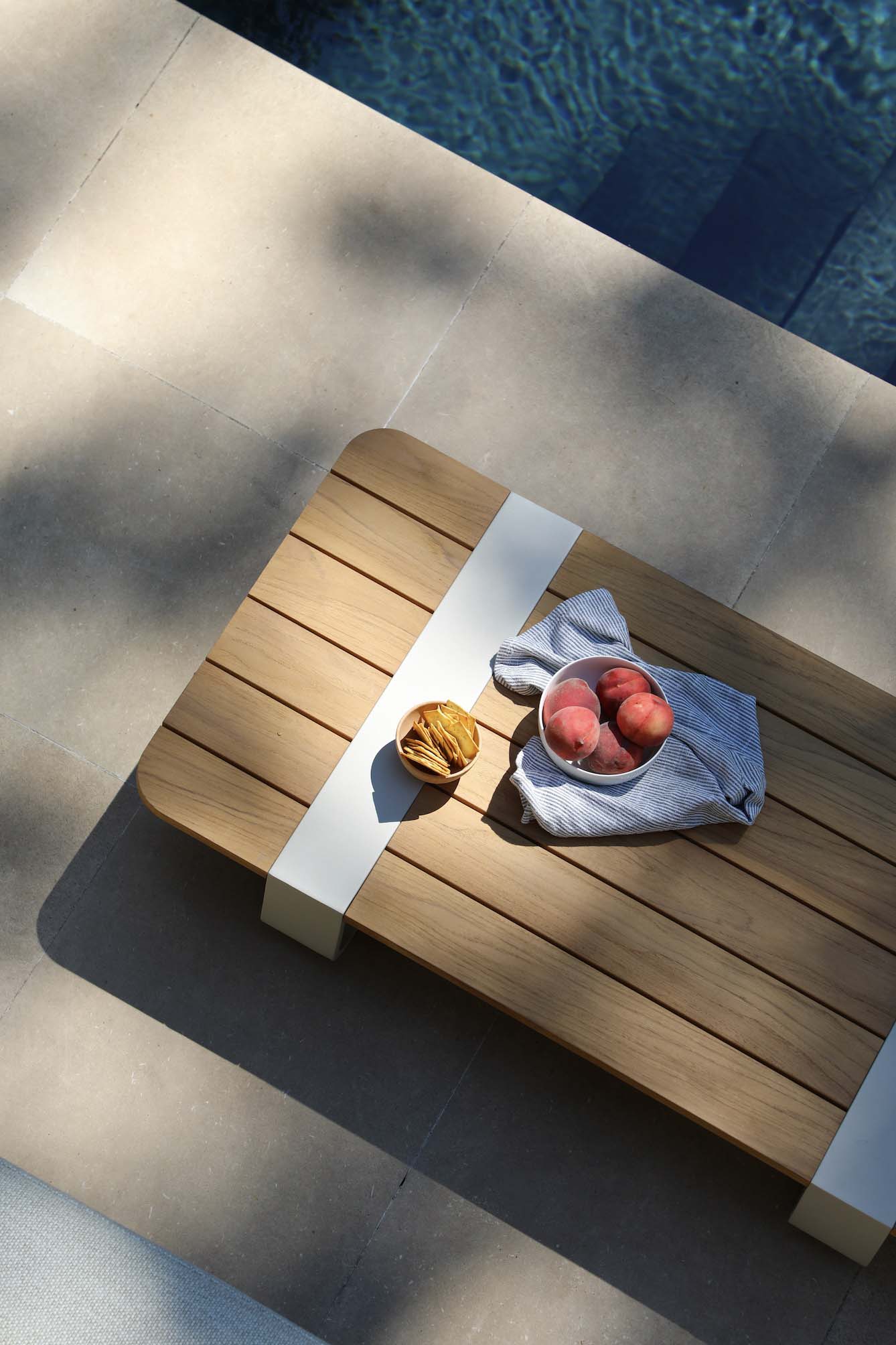 Table basse d'angle en aluminium design beige avec plateau en teck FSC luxueux, ambiance méditerranéenne, tissu.