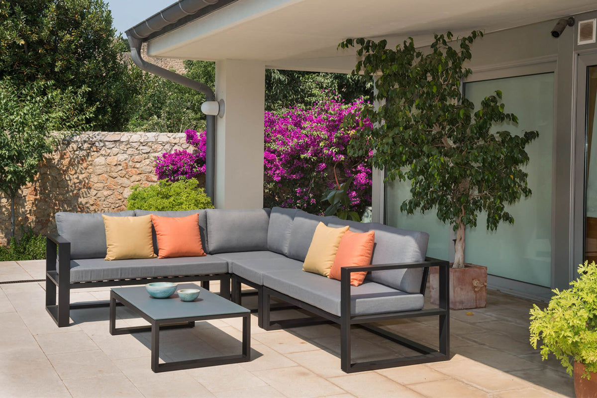 Salon de jardin modulable haut de gamme en aluminium noir, design élégant méditerranéen avec coussins gris et touches.
