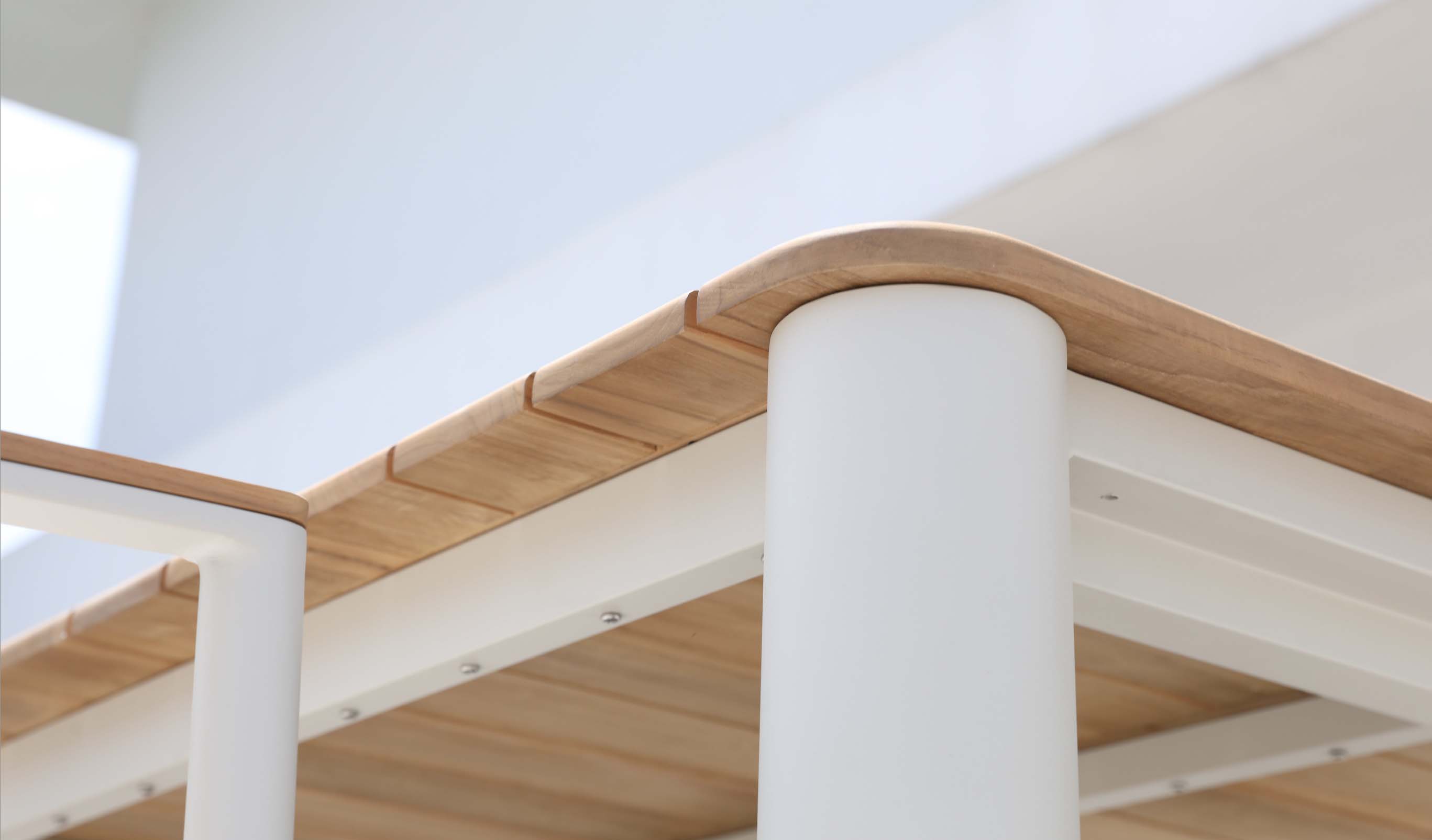 Table repas extérieur avec plateau en teck FSC chaleureux et pieds ronds cylindriques en aluminium haut de gamme inoxydable.