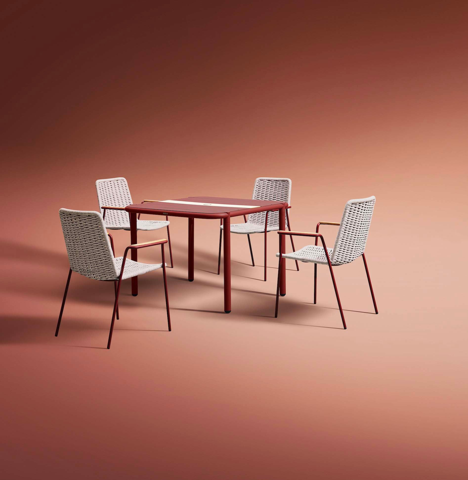 Table bistrot carré rouge en aluminium thermolaqué, design épuré et élancé, chaise assortie en rotin synthétique beige.