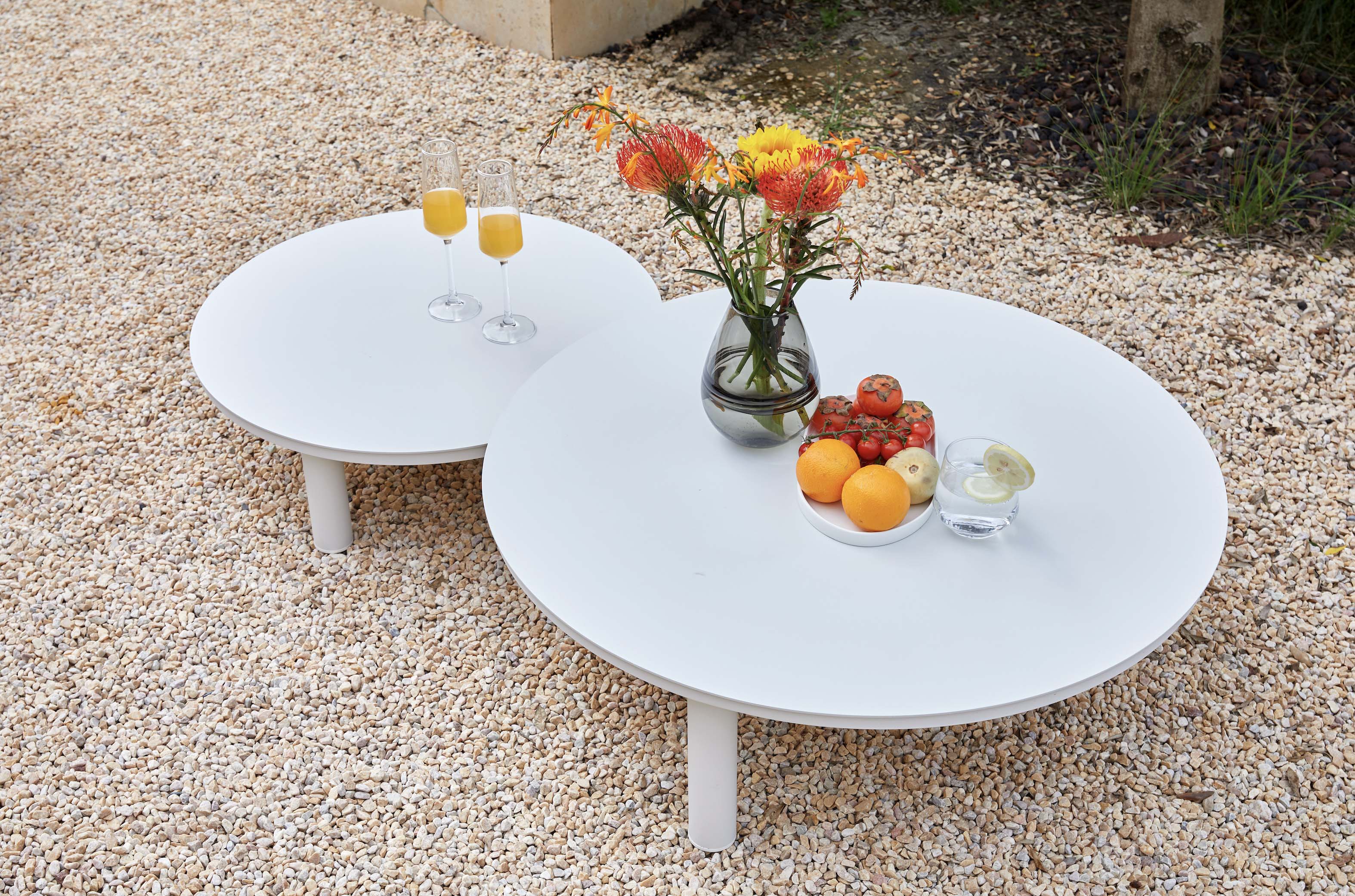 Tables basses rondes en aluminium haut de gamme blanc avec plateaux en céramique, design luxe et épuré, posées sur sol.
