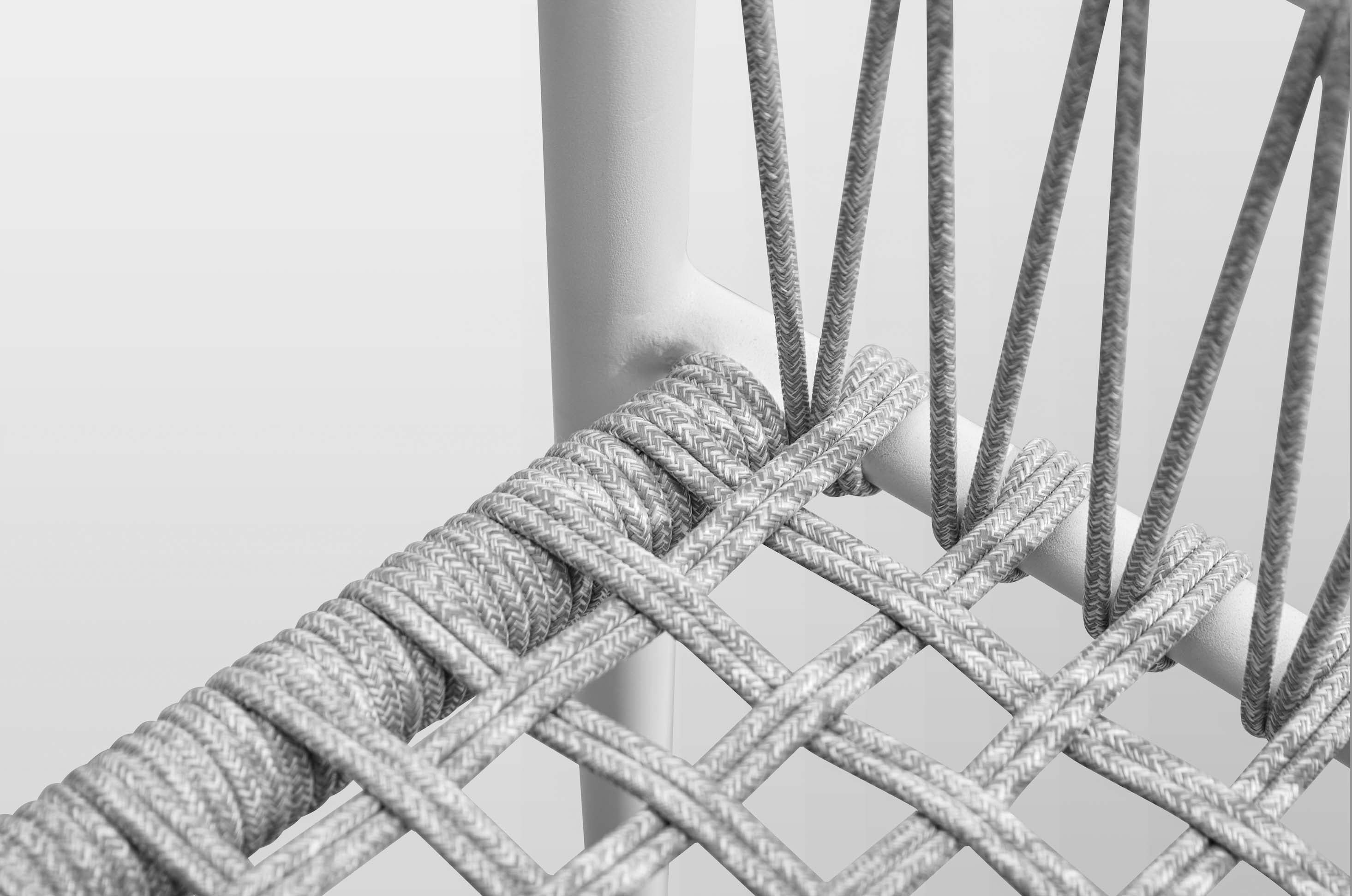 Détail de corde tressée beige sur structure aluminium blanc, chaise bistrot haut de gamme pour terrasse de restaurant. 