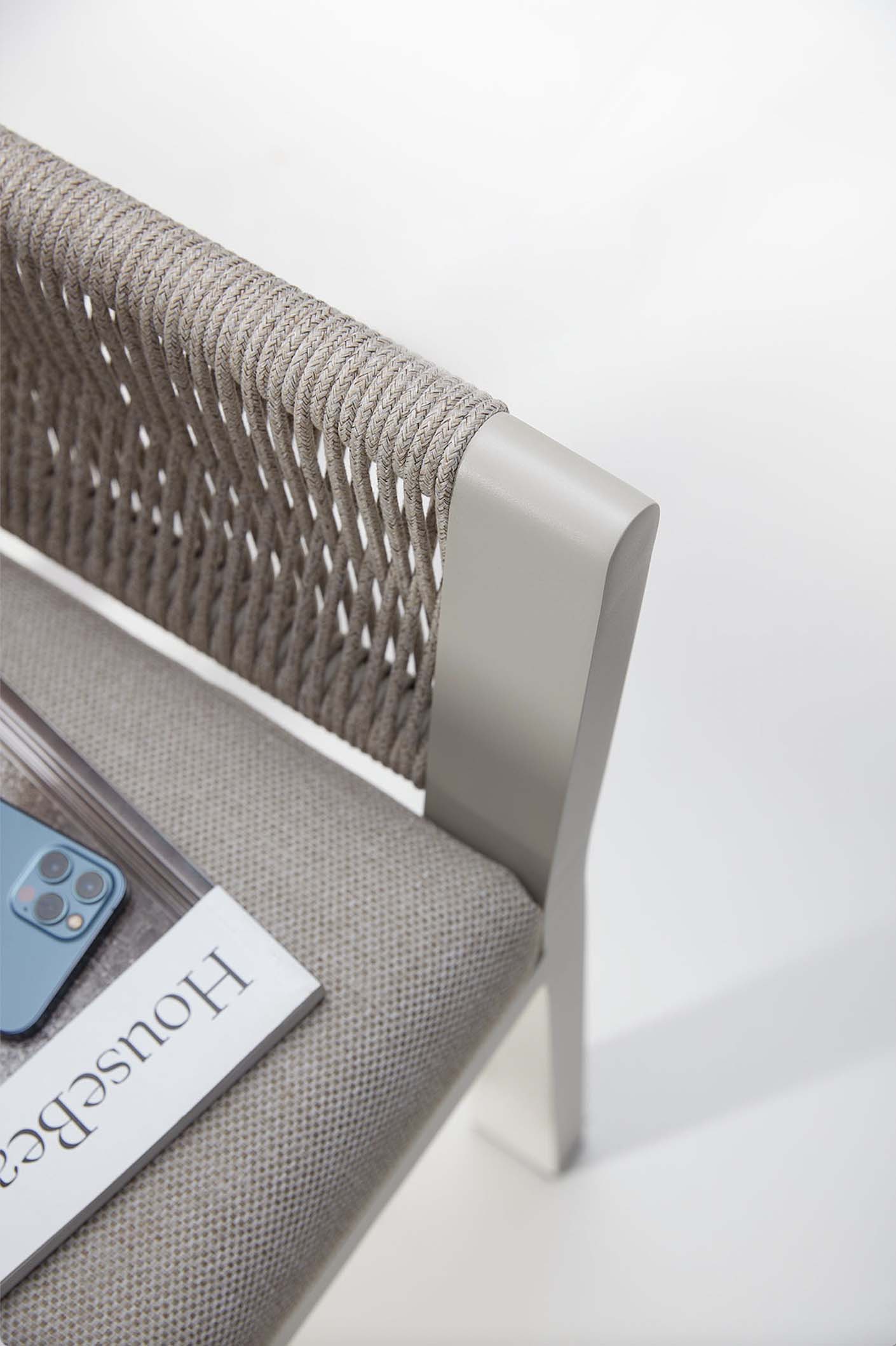 Coin d’une chaise d’extérieur moderne avec structure en aluminium, dossier en corde tressée beige, coussin gris déhoussable.