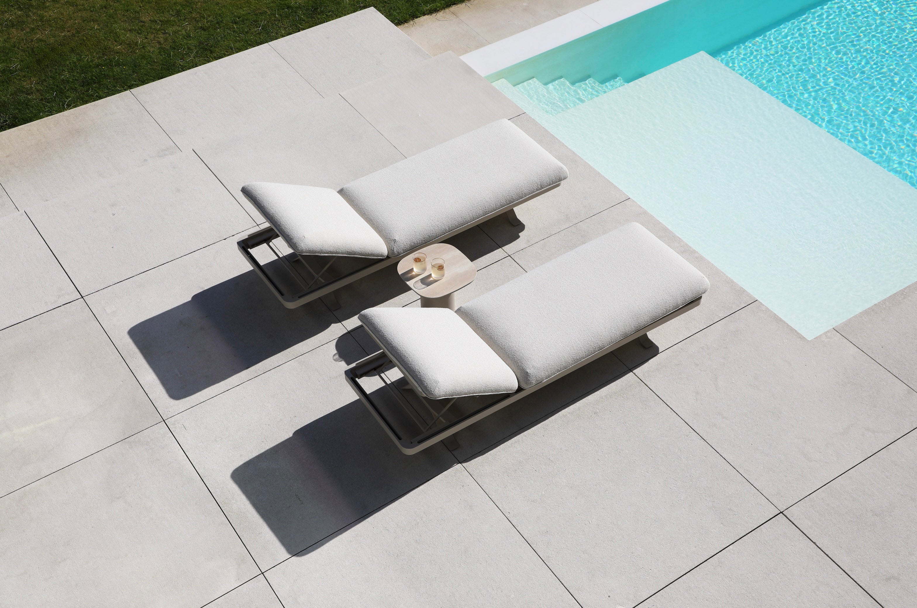 Salon de jardin d'angle modulable en aluminium inoxydable avec coussins déhoussables et déperlants, assise élégante au bord.