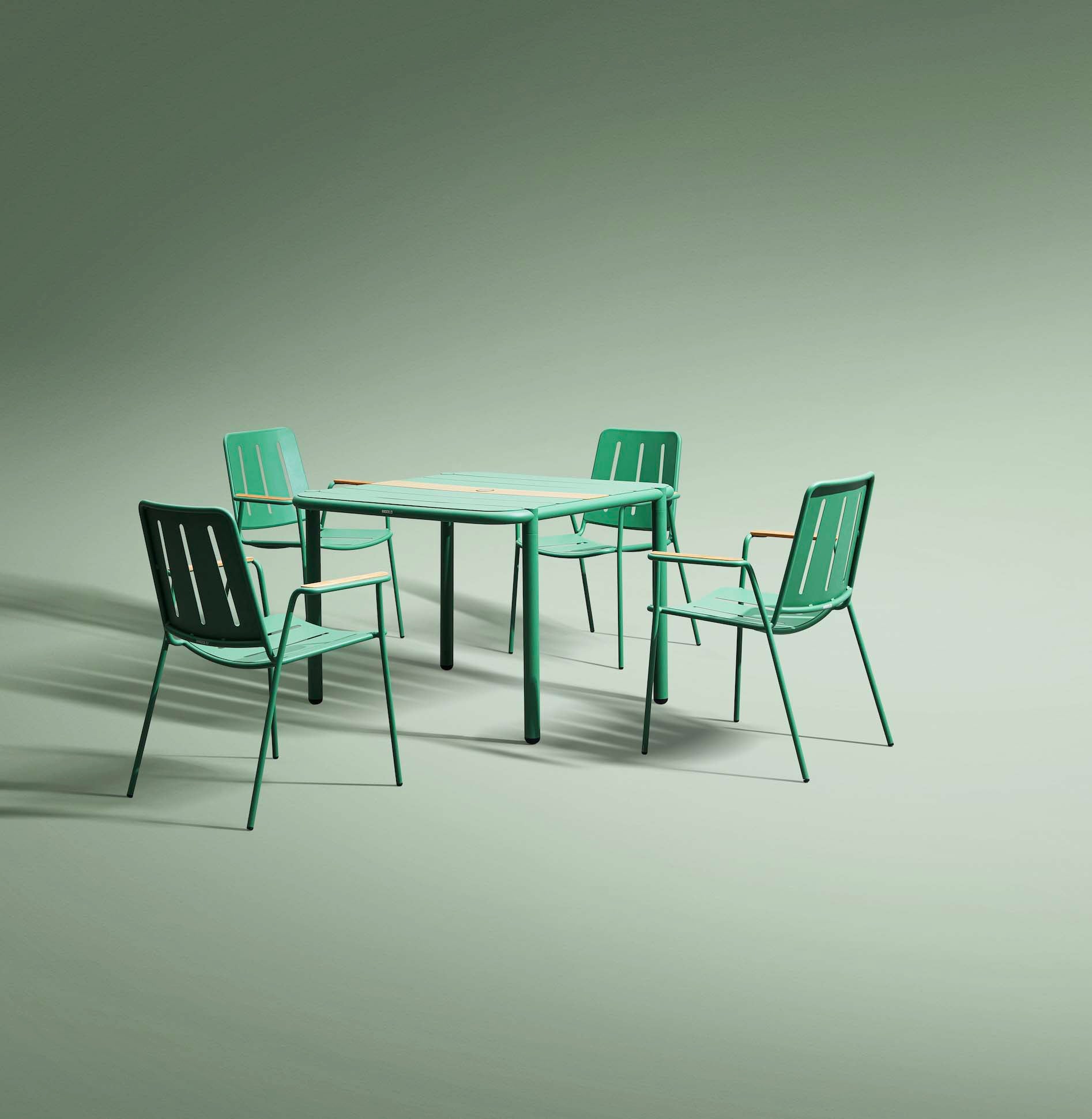 Ensemble bistrot haut de gamme en aluminium vert, quatre chaises design empilables avec dossiers ajourés, table carrée.
