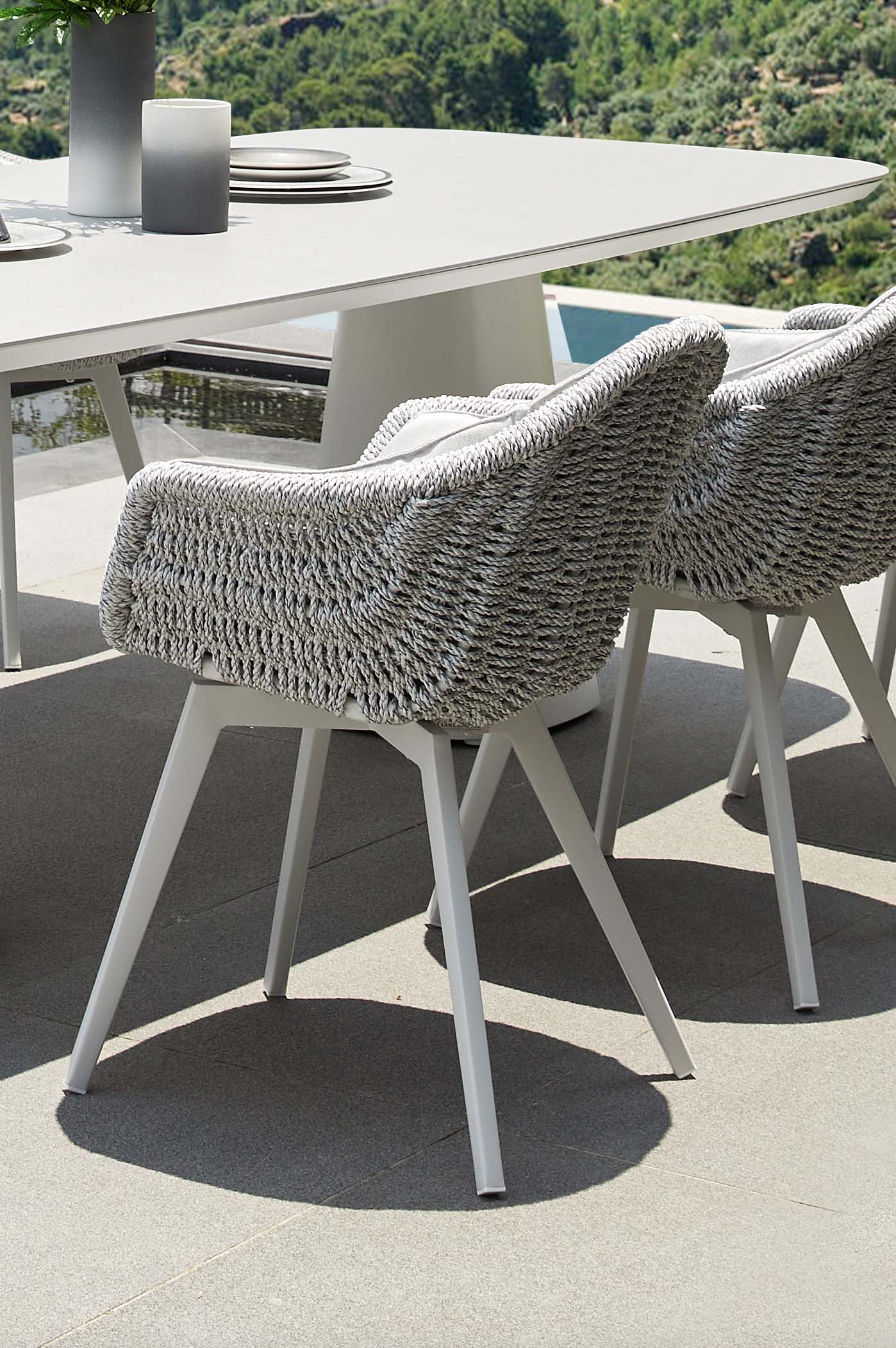 Fauteuil repas extérieur en aluminium haut de gamme blanc avec résine tressée, coussins blancs élégants, pieds au design.