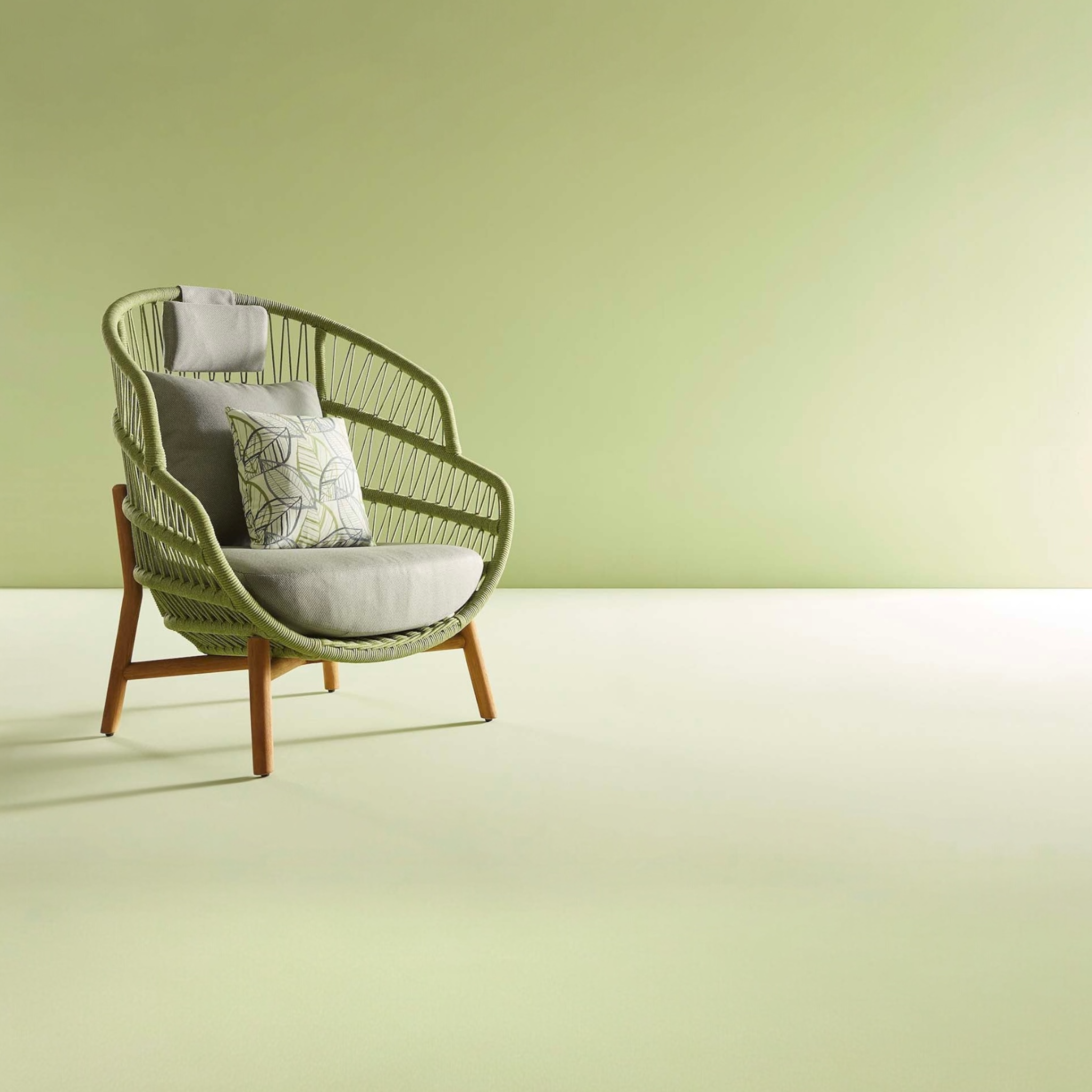 Fauteuil extérieur en corde verte avec dossier haut arrondi et coussins gris