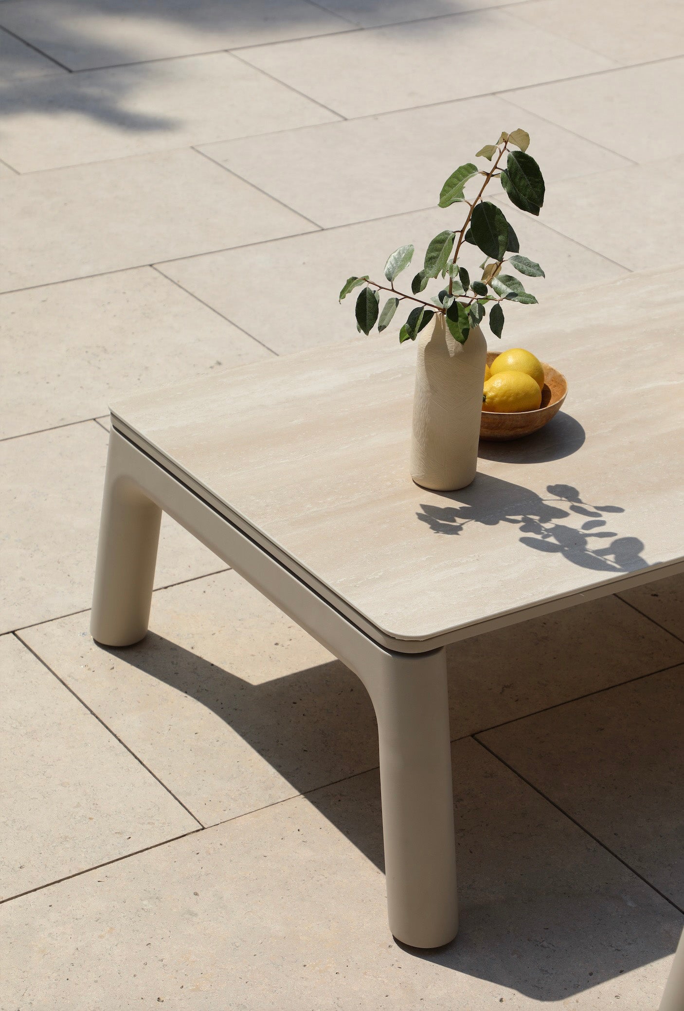 Table basse modulable en aluminium inoxydable beige avec plateau en céramique, design luxe et épuré, ambiance.