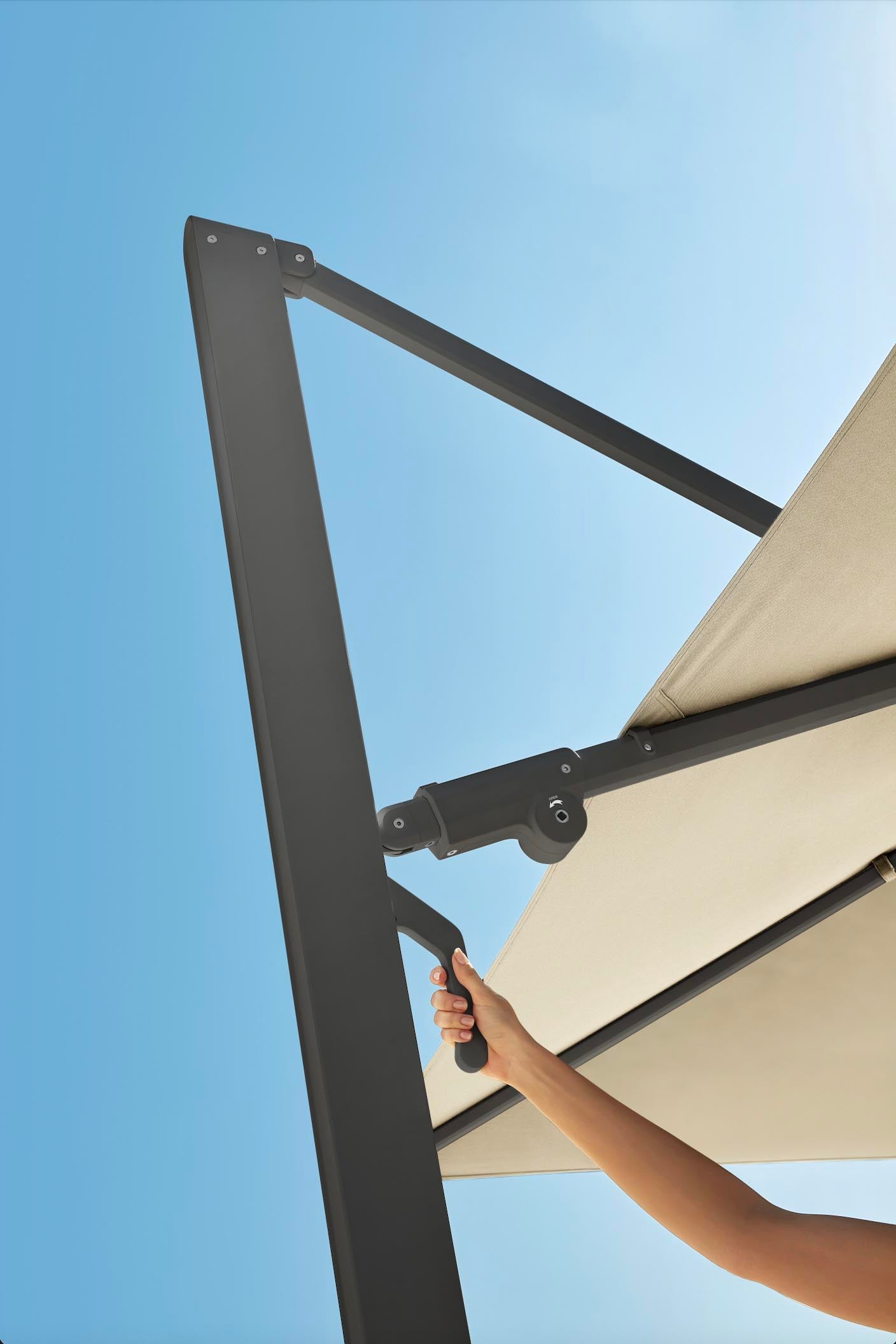 Structure aluminium gris mat du parasol déporté haut de gamme, toile Sunbrella beige, design luxueux signé Pininfarina,.