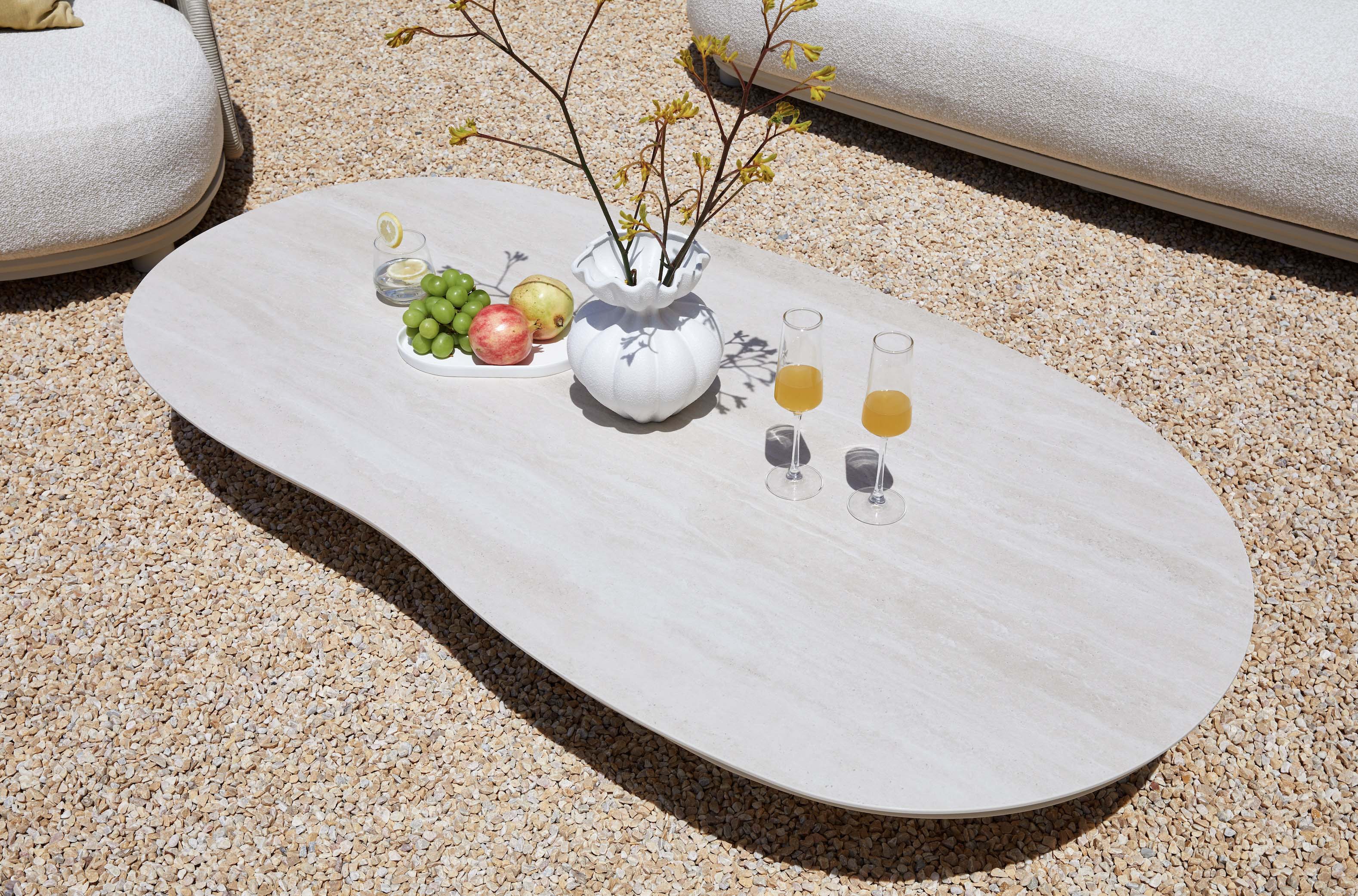 Table basse ovale en aluminium design beige avec plateau céramique, surface lisse et élégant style méditerranéen. 