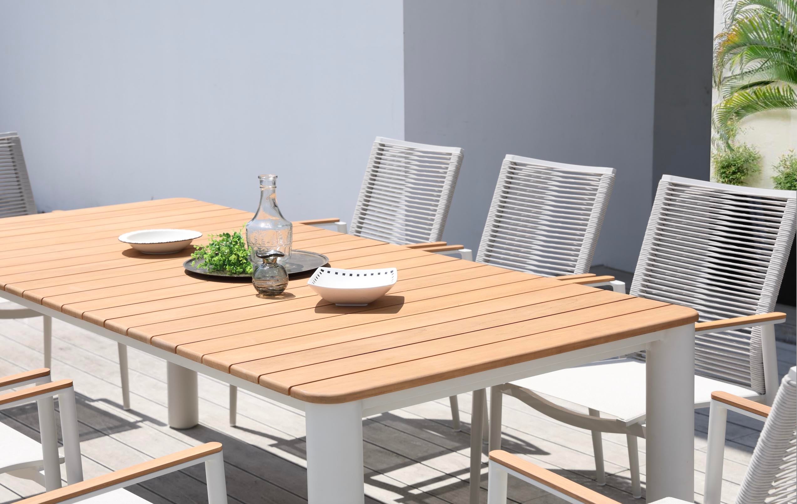 Table repas extérieur design avec plateau en teck FSC chaleureux, pieds ronds cylindriques en aluminium haut de gamme.