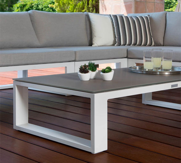 Salon de jardin modulable haut de gamme en aluminium blanc, canapé d’angle gris clair avec coussins élégants et table basse.