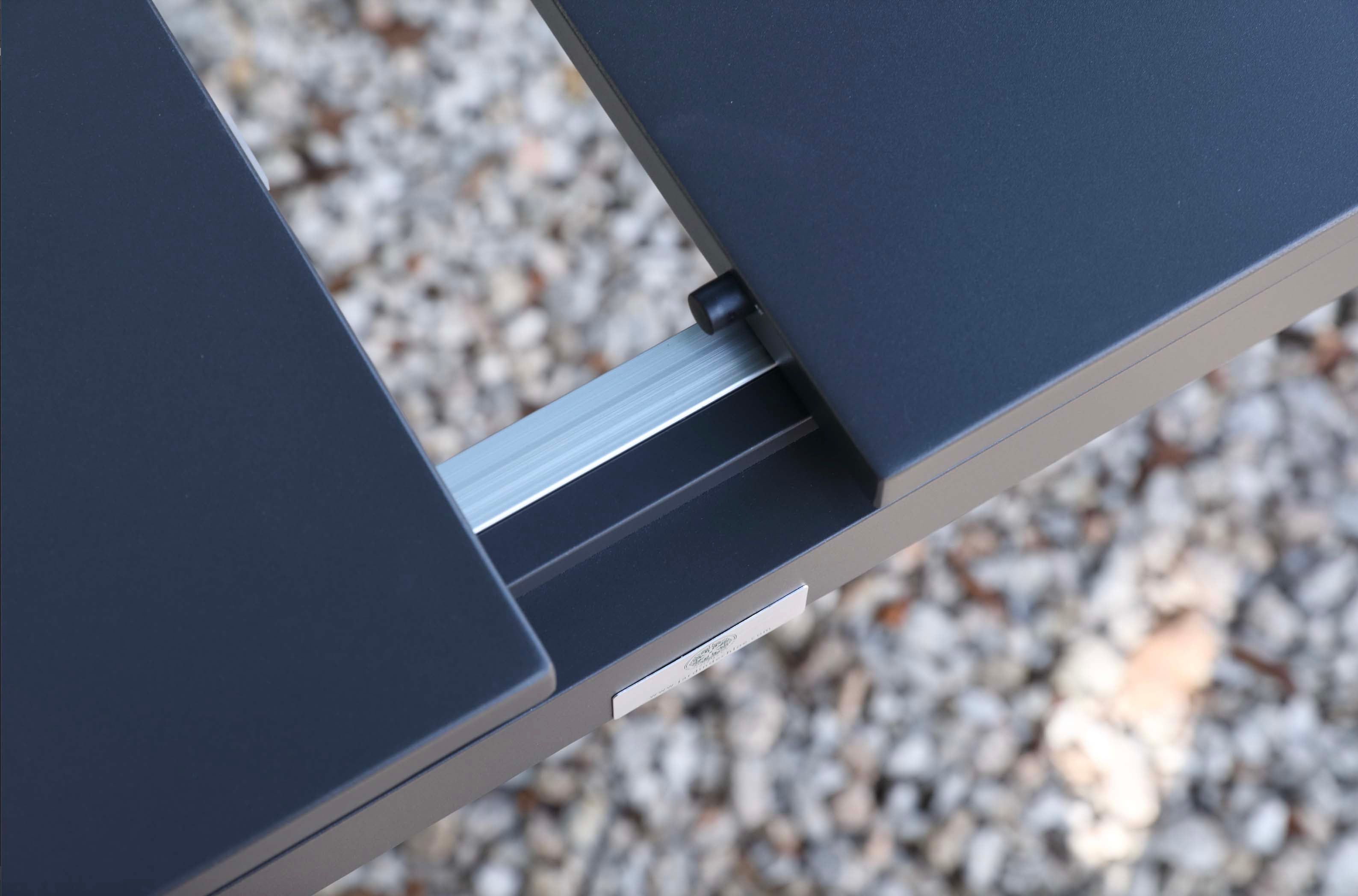 Table extensible en aluminium haut de gamme inoxydable noir mat, mécanisme solide en aluminium visible, design épuré.