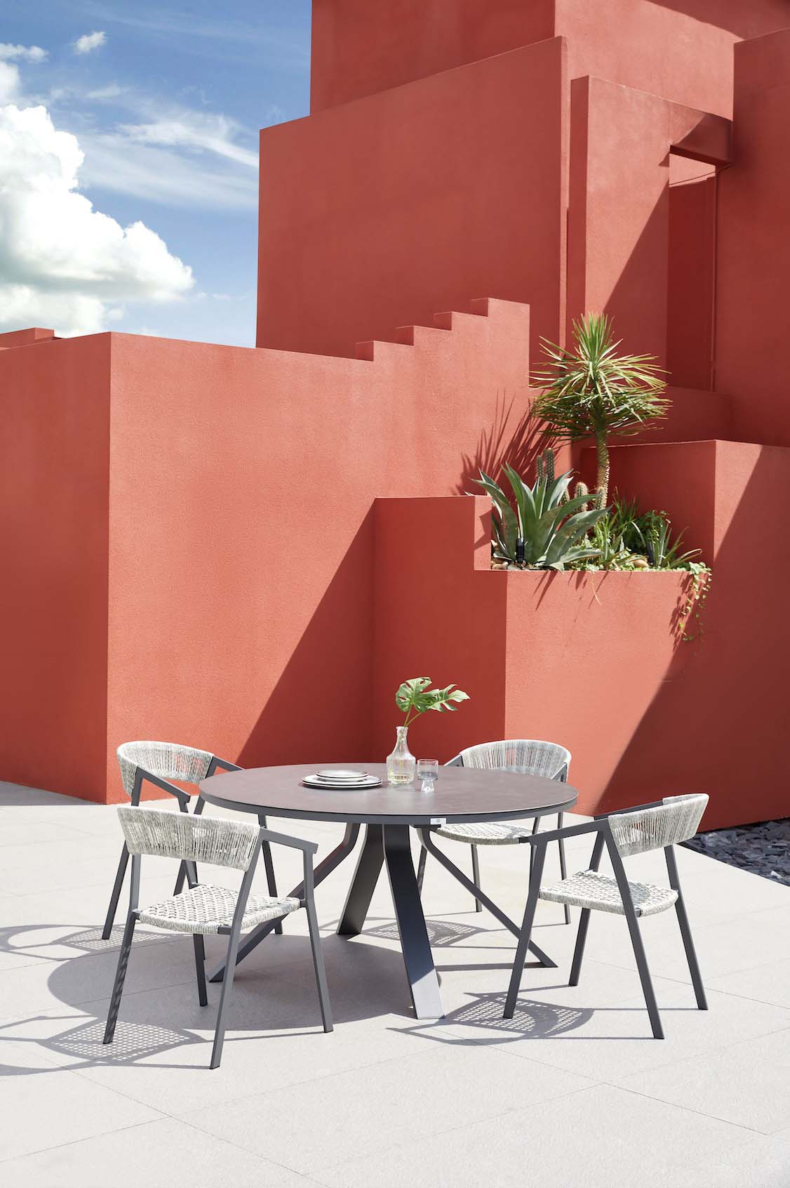 Table ronde élégante en aluminium haut de gamme noir avec plateau en verre sécurit, design moderne et durable, chaises.