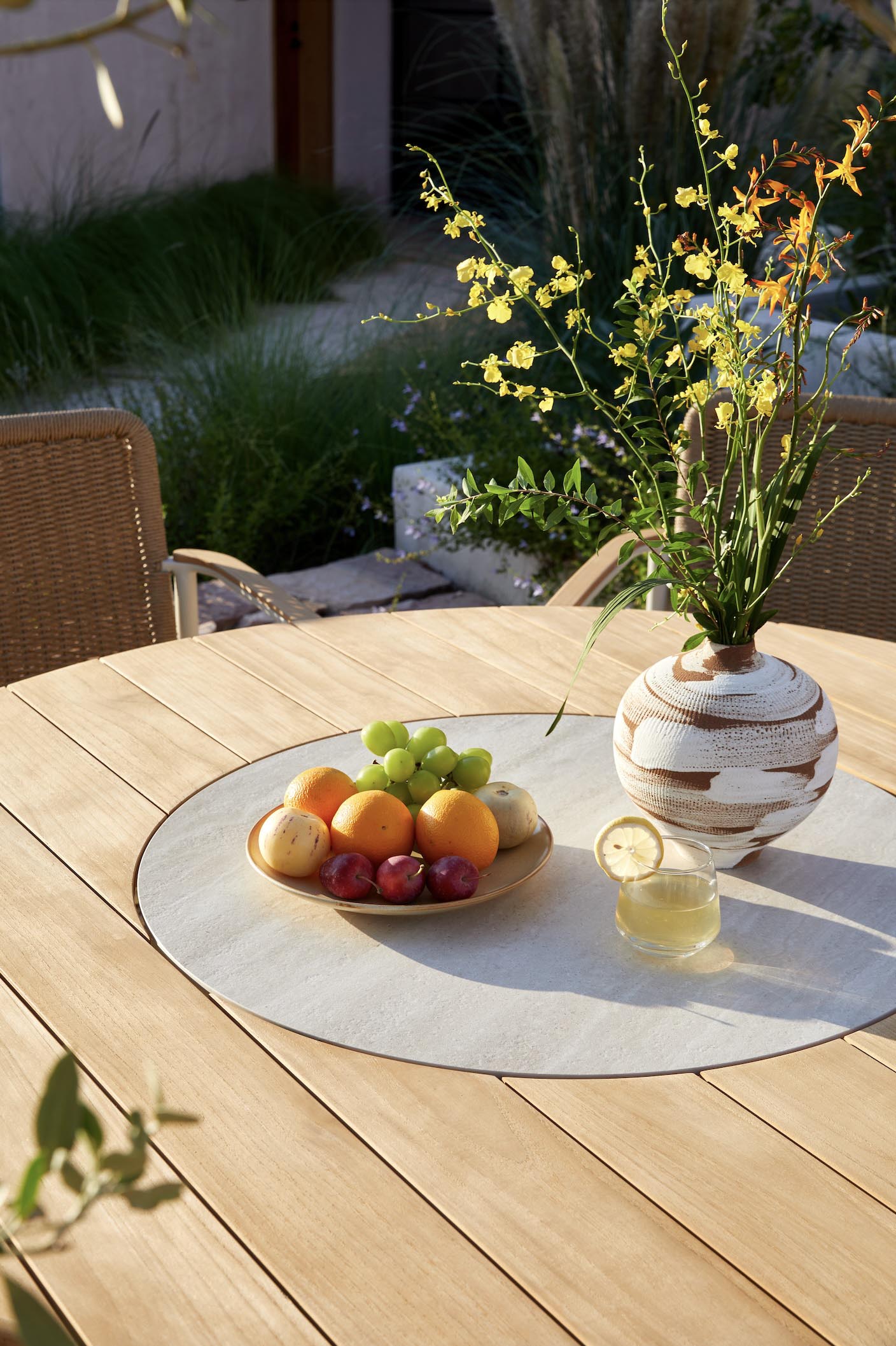 Détail du plateau de la table ARIEL en teck et en céramique sur le centre. 