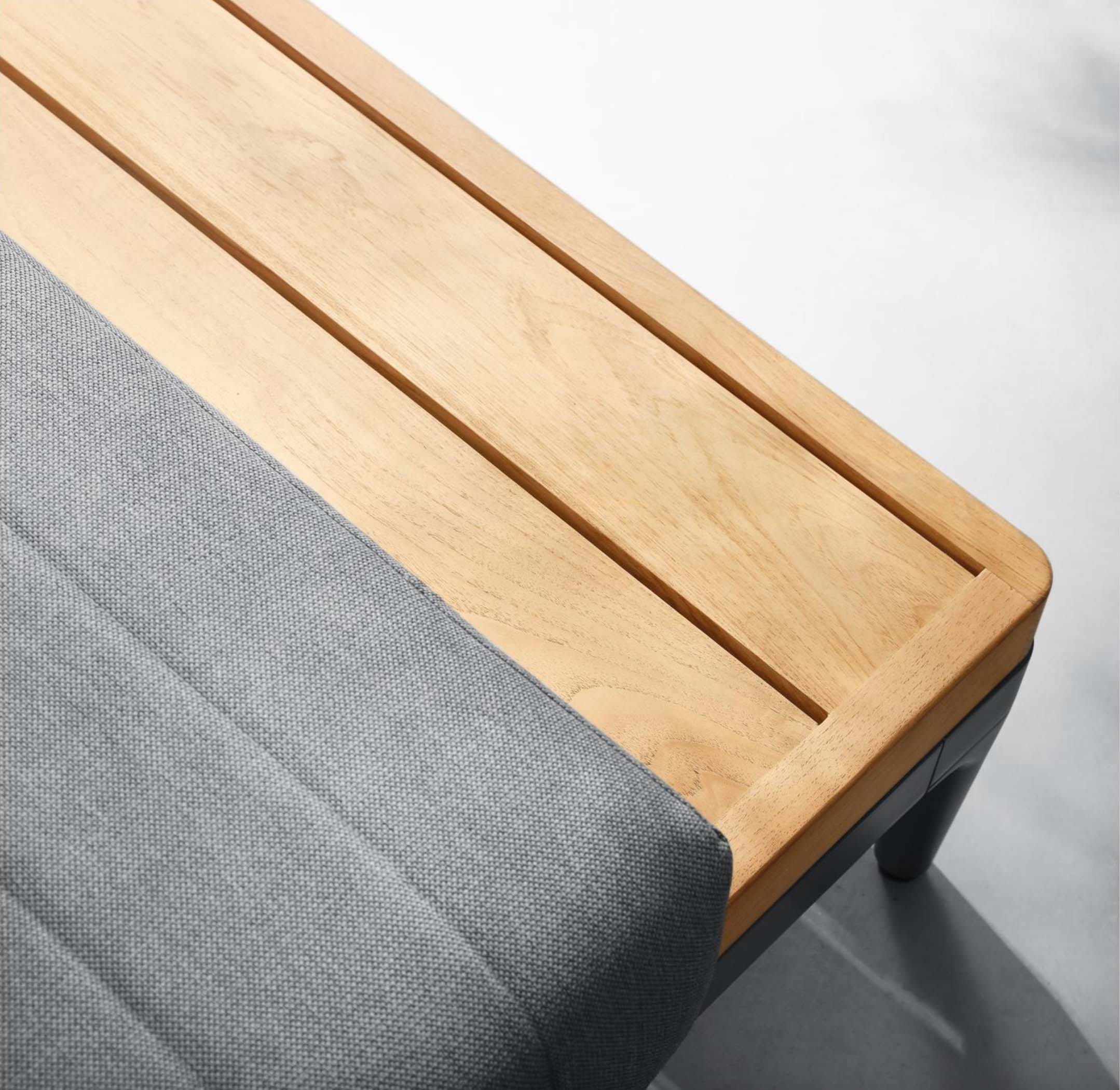 Détail plateau en teck FSC clair aux lignes épurées sur structure aluminium inoxydable, coussin gris en tissu 100% Oléfine.